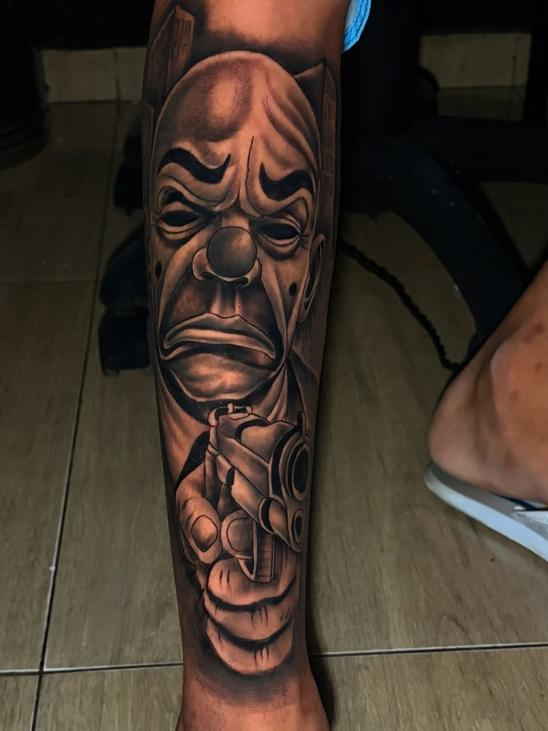 Tatuagem de máscara expressiva em realismo, com volume e sombras em preto e cinza