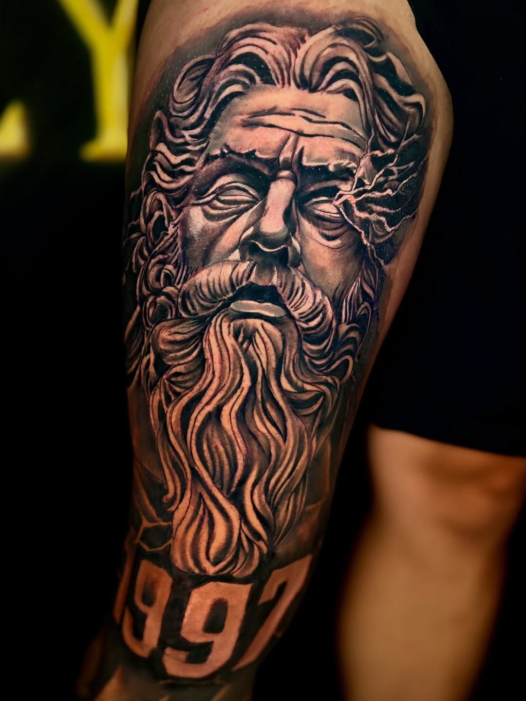 Rosto masculino de inspiração clássica com barba detalhada tatuado no braço